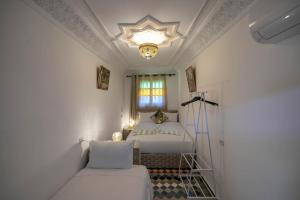 a white bedroom with a bed and a chandelier at Riad dar Yamna in Fès