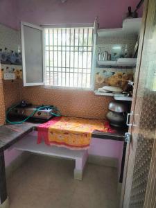 una cocina con mesa y ventana. en jharana guest house en Puri