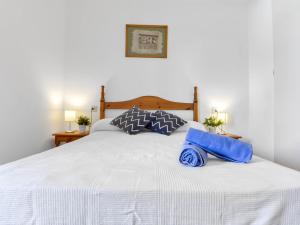 ein weißes Bett mit zwei blauen Kissen darauf in der Unterkunft Apartment Platja de Roses-7 by Interhome in Roses