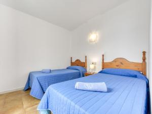 1 dormitorio con 2 camas con edredones azules y almohada en Apartment Platja de Roses-8 by Interhome, en Roses