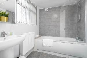 a white bathroom with a tub and a sink at Stylish 3 Bedroom House - WIFI - NETFLIX - Parking - Garden - 11T in Birmingham