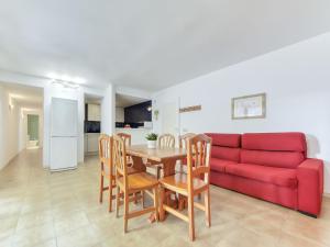 a living room with a red couch and a table and chairs at Apartment Platja de Roses-11 by Interhome in Roses