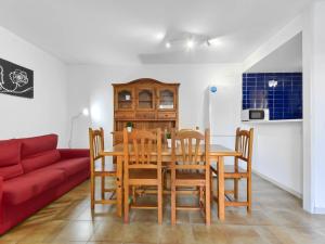a dining room with a table and chairs and a red couch at Apartment Platja de Roses-9 by Interhome in Roses