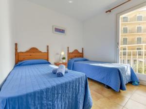 ロザスにあるApartment Platja de Roses-5 by Interhomeのベッドルーム(青いシーツ、窓付)のベッド2台