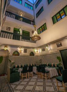 Habitación grande con mesas, sillas y lámpara de araña. en Riad dar Yamna en Fez
