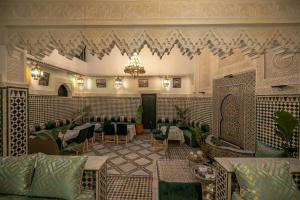 un restaurante con mesas y sillas y una lámpara de araña en Riad dar Yamna en Fez