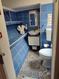 a blue tiled bathroom with a toilet and a sink at A' casuzza in Palermo