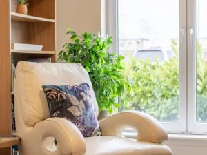 a white chair with a pillow and a window at Pass the Keys Comfortable and Fabulous Family Home in Newton Mearns