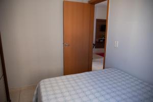 a bedroom with a bed and a wooden door at Apto otima localizacao e Wi-Fi em Serra ES in Serra
