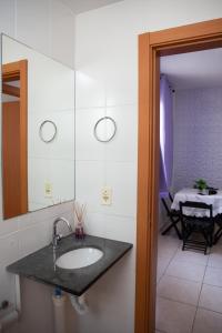 a bathroom with a sink and a mirror and a table at Apto otima localizacao e Wi-Fi em Serra ES in Serra