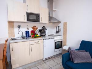 eine kleine Küche mit weißen Schränken und einer blauen Couch in der Unterkunft Apartment Achtern Diek by Interhome in Norddeich