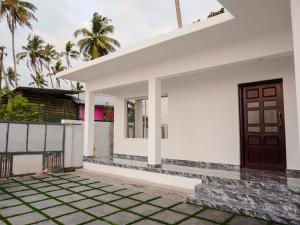 Casa blanca con puerta marrón en Marari Aidenz Beach Vibe Villa en Alleppey