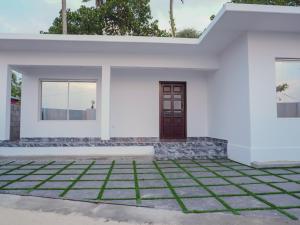 een wit huis met een deur en gras bij Marari Aidenz Beach Vibe Villa in Alleppey