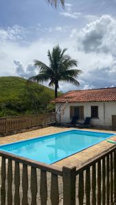 a swimming pool in front of a house with a palm tree at Chácara De Paula in Vassouras