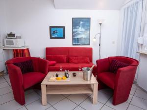 ein Wohnzimmer mit zwei roten Stühlen und einer roten Couch in der Unterkunft Apartment Am Deich by Interhome in Norddeich