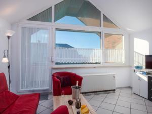 ein Wohnzimmer mit einem roten Stuhl und einem Fenster in der Unterkunft Apartment Am Deich by Interhome in Norddeich