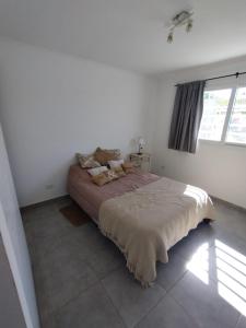 um quarto com uma cama grande num quarto branco em La Casita en Tandil em Tandil