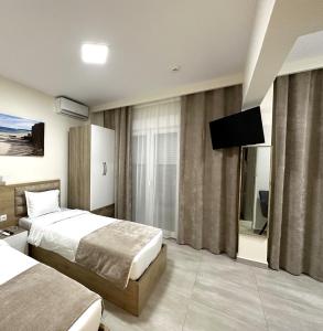 a hotel room with two beds and a flat screen tv at Navarino Luxe Suites with Sea View in Perea