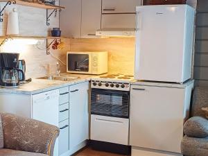 uma cozinha com um frigorífico e um fogão forno superior em Holiday Home Mustalampi 4 kyyhkynen by Interhome em Ruka