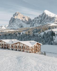 un bâtiment dans la neige avec une montagne en arrière-plan dans l'établissement Brunelle Seiser Alm Lodge, à Alpe di Siusi