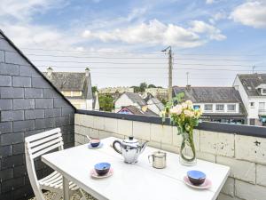 a white table with a vase of flowers on a balcony at Apartment Les Embruns-1 by Interhome in Carnac