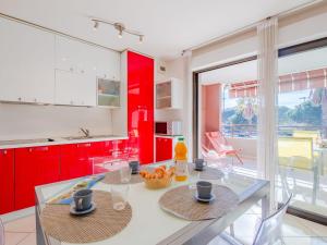 a kitchen with red cabinets and a glass table at Apartment Santa Monica-1 by Interhome in Fréjus