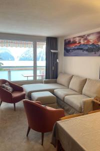 ein Wohnzimmer mit einem Sofa und einem großen Fenster in der Unterkunft Apartment Promenade - Utoring-79 by Interhome in Arosa