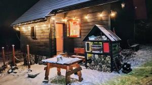 eine kleine Holzhütte mit einem Tisch davor in der Unterkunft Beskidzka Ostoja in Koszarawa