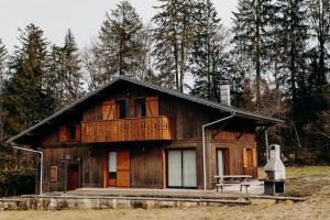 een groot houten huis met een bankje ervoor bij Chalet des bois de Criou in Morillon