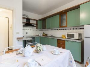 una cocina con armarios verdes y una mesa con tazas de té. en Apartment Gallesio - FLG213 by Interhome en Finale Ligure