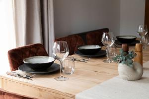 uma mesa de madeira com copos de vinho e pratos em Chalet des bois de Criou em Morillon