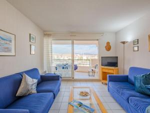 uma sala de estar com um sofá azul e uma televisão em Apartment Le Borghese by Interhome em Fréjus