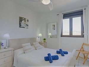 a white bedroom with a bed with blue pillows on it at Apartment Galicia Javea-2 by Interhome in Jávea