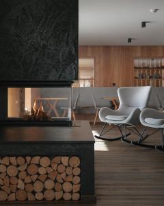 a living room with a fireplace and two chairs at Brunelle Seiser Alm Lodge in Alpe di Siusi