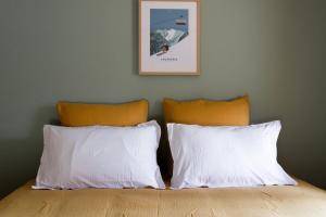 een bed met twee witte kussens en een foto aan de muur bij Chalet des bois de Criou in Morillon