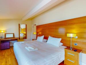 sypialnia z dużym białym łóżkiem z drewnianym zagłówkiem w obiekcie Holiday Home Castlemartyr Holiday Lodge by Interhome w Cork