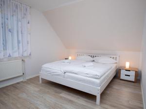 een witte slaapkamer met een wit bed en 2 kaarsen bij Holiday Home Nilles by Interhome in Norddeich