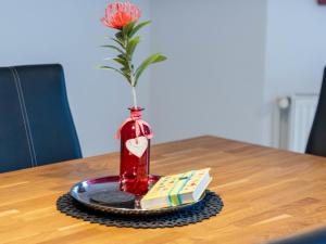 a red vase with a flower in it on a table at Holiday Home Nilles by Interhome in Norddeich +41 photos