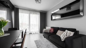a living room with a black couch and a table at Flatbook - City Center SPA Apartments 6B,C in Gdańsk