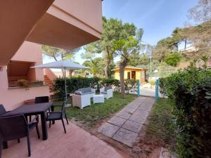 une terrasse avec une table, des chaises et un parasol dans l'établissement Lido I Palmizi, à Capoliveri