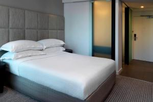 um quarto com uma cama grande com lençóis brancos e almofadas em Four Points by Sheraton Brisbane em Brisbane