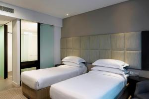 two twin beds in a room with a wall at Four Points by Sheraton Brisbane in Brisbane