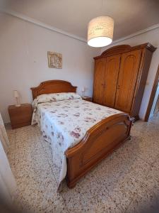 Schlafzimmer mit einem großen Bett mit einem Kopfteil aus Holz in der Unterkunft Maison santa pola in Santa Pola