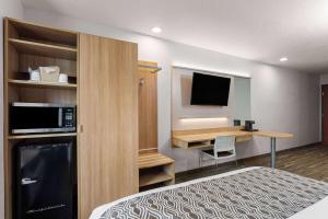 ein Hotelzimmer mit einem Bett und einem Schreibtisch mit Fernseher in der Unterkunft Microtel Inn and Suites - Zephyrhills in Zephyrhills