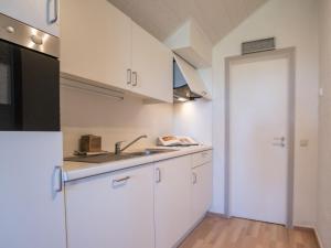 a kitchen with white cabinets and a sink at Apartment Dina with parking and shared pool by Interhome in De Haan