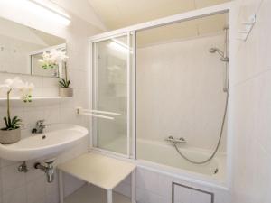 a white bathroom with a shower and a sink at Apartment Dina with parking and shared pool by Interhome in De Haan