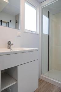 a white bathroom with a sink and a shower at Holiday Home Natuurlijk de Veenhoop by Interhome in De Veenhoop