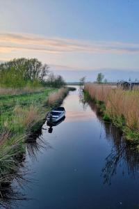 a boat is sitting in the middle of a river at Holiday Home 4-persoons Doutzen by Interhome in De Veenhoop