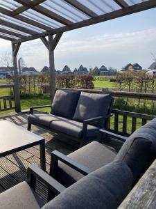 a patio with a couch and chairs on a deck at Holiday Home 4-persoons Doutzen by Interhome in De Veenhoop