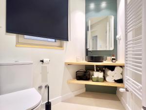 a bathroom with a toilet and a tv on the wall at Housing León San Pedro in León